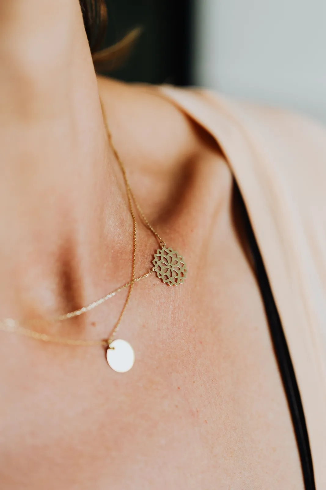 Layered fine gold necklaces worn on a collarbone in warm light