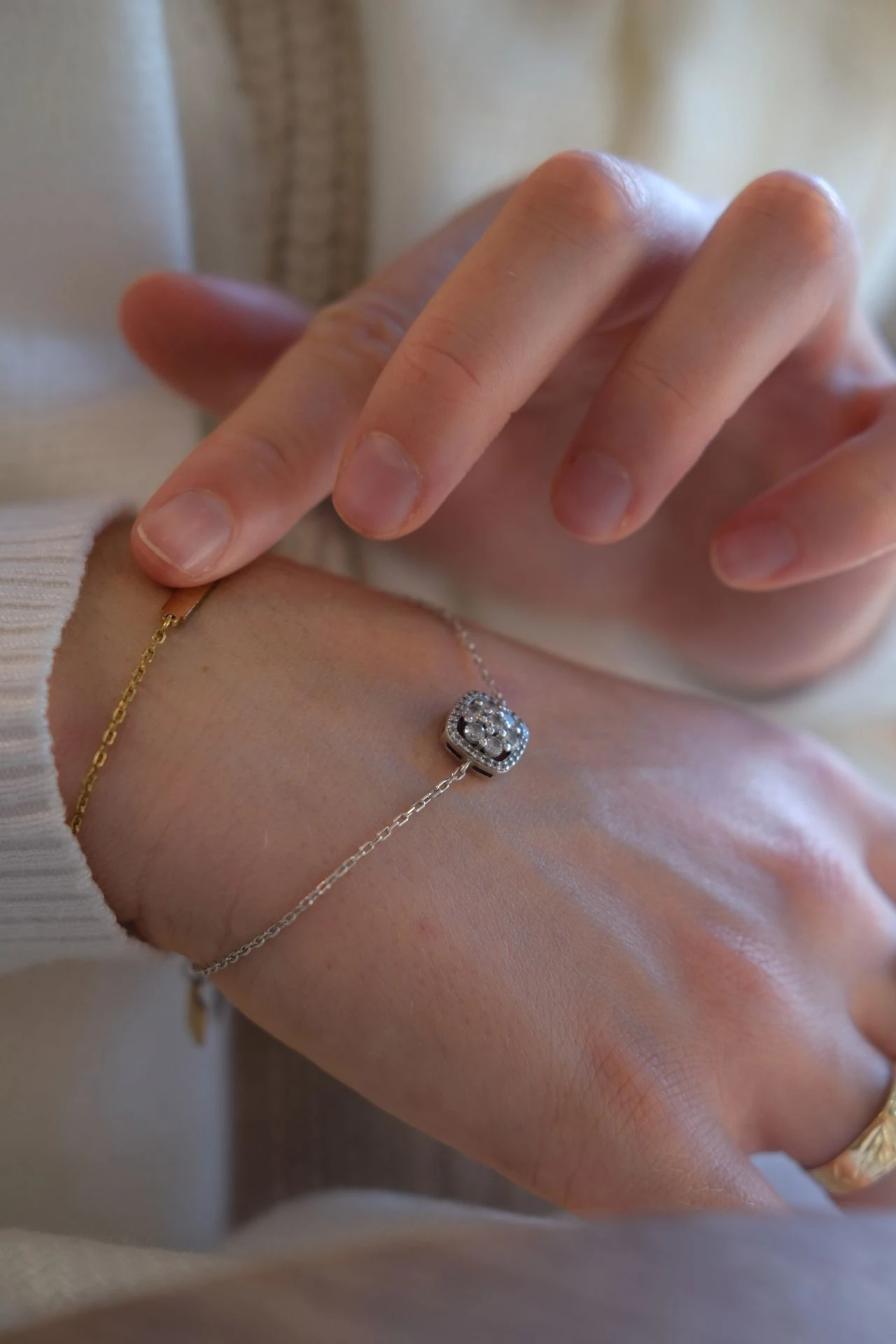 Two fine gold chains layered snug on a wrist in warm light.